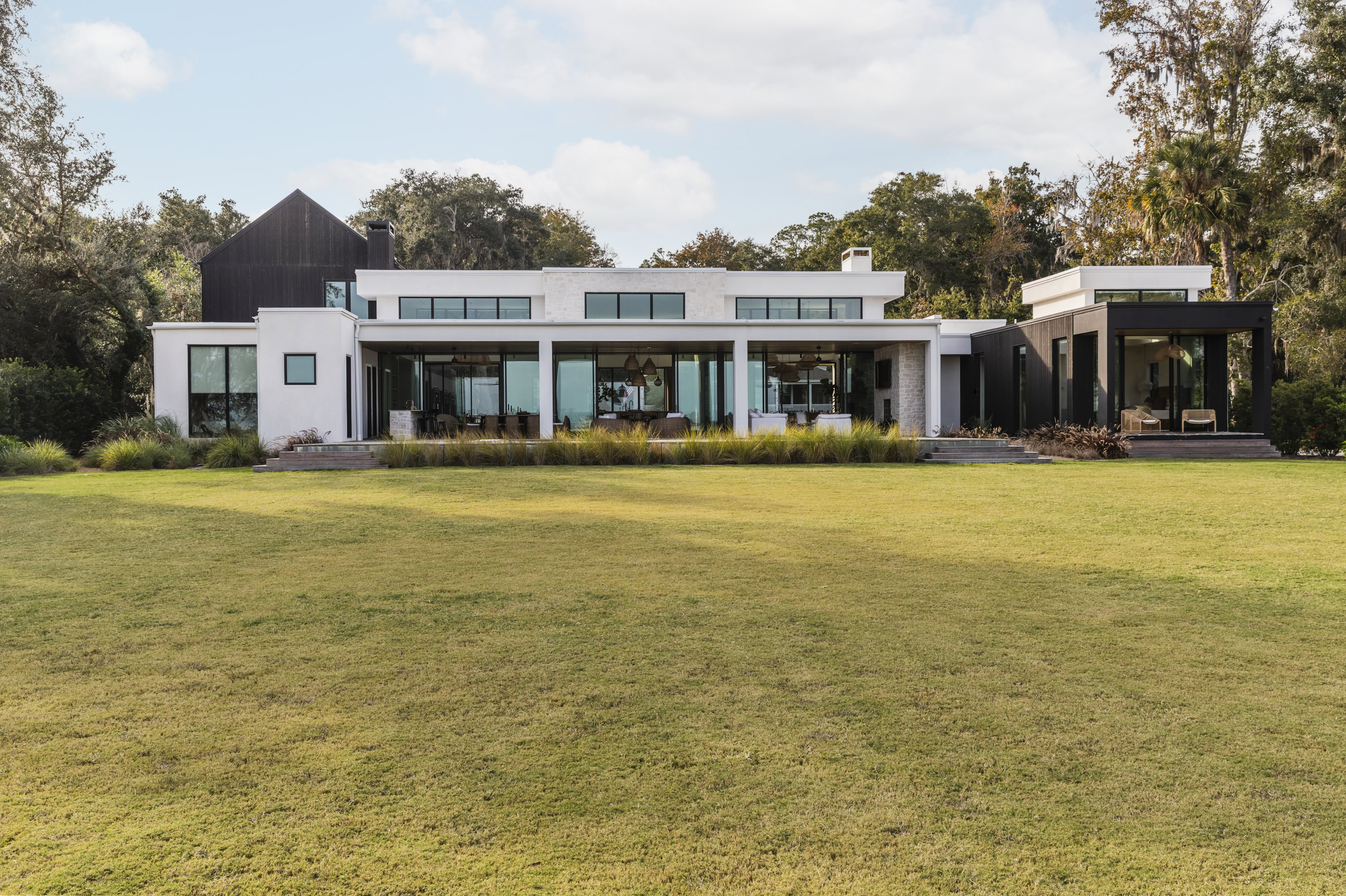 Modern contemporary house with large glass windows and spacious lawn.