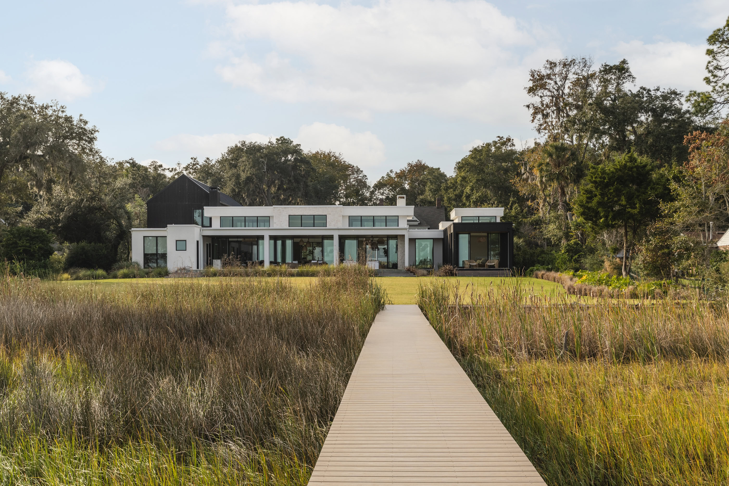Modern contemporary house with large glass windows and spacious outdoor area.