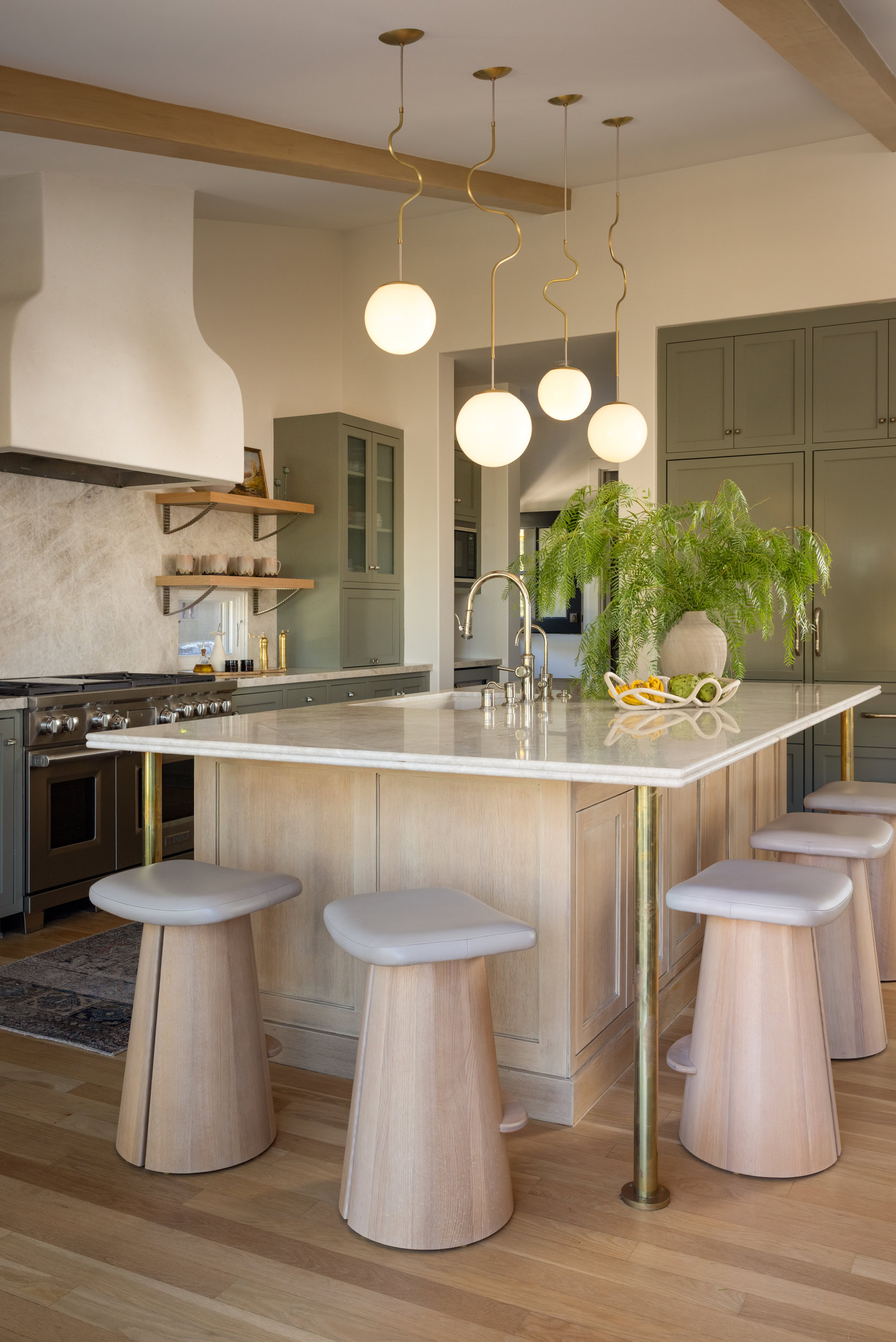 Bright and stylish kitchen featuring green cabinetry, a marble island, and contemporary pendant ligh.