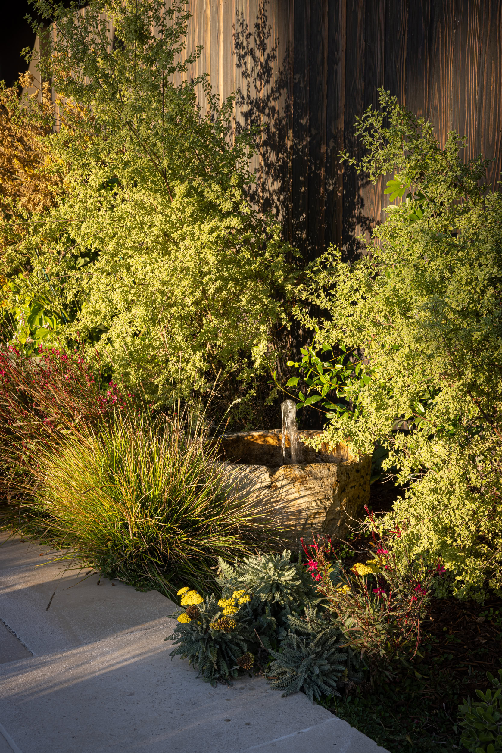 Beautiful garden with lush greenery and a small fountain, showcasing stylish outdoor interior design.