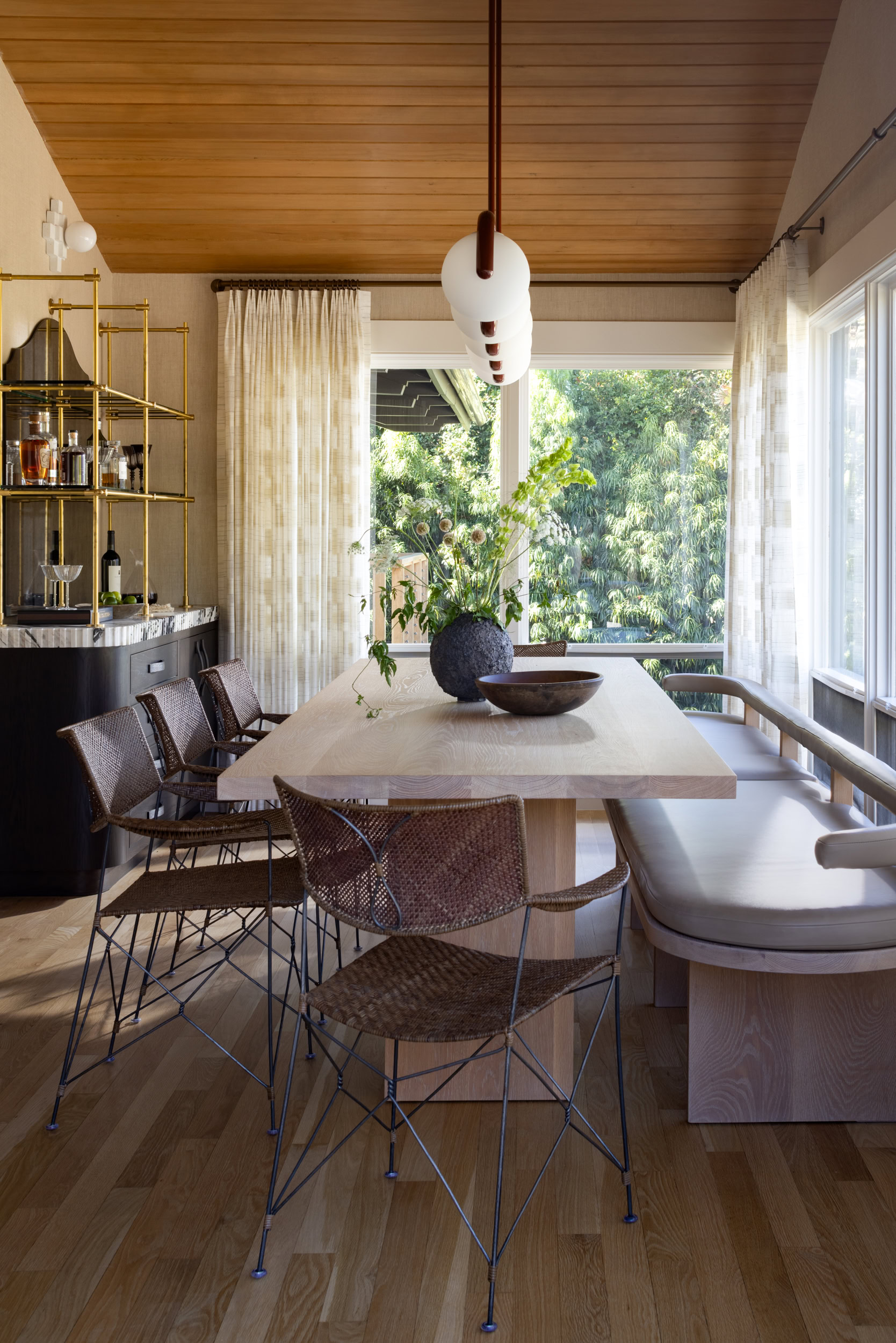 Bright dining area with stylish furniture and lush greenery outside.