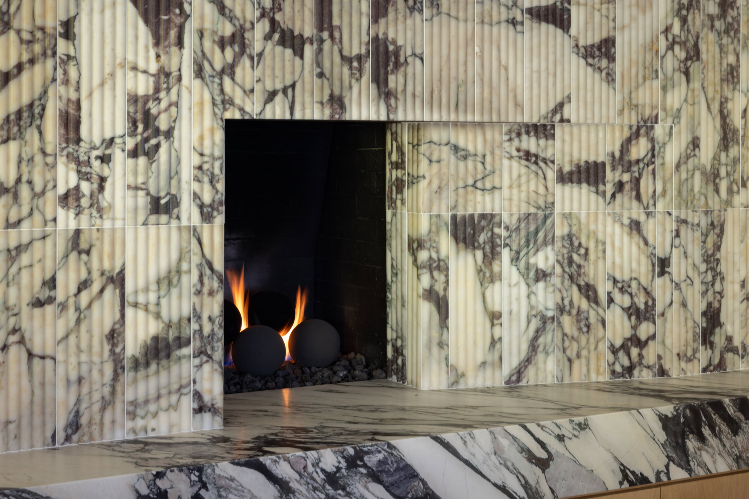 Modern marble fireplace with sleek design and warm fire ambiance.