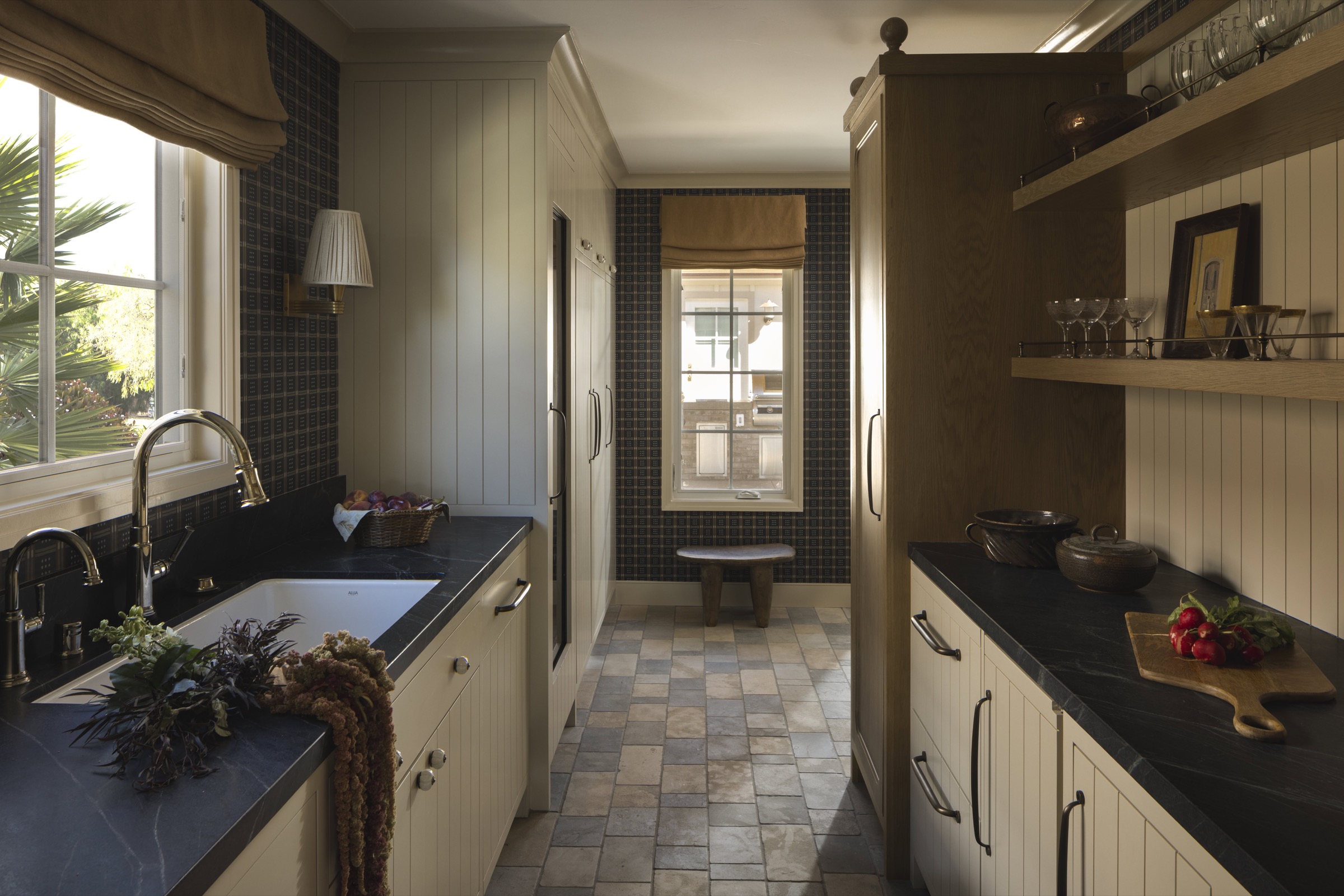 Bright kitchen with white cabinetry and black countertops, featuring natural light from large window.