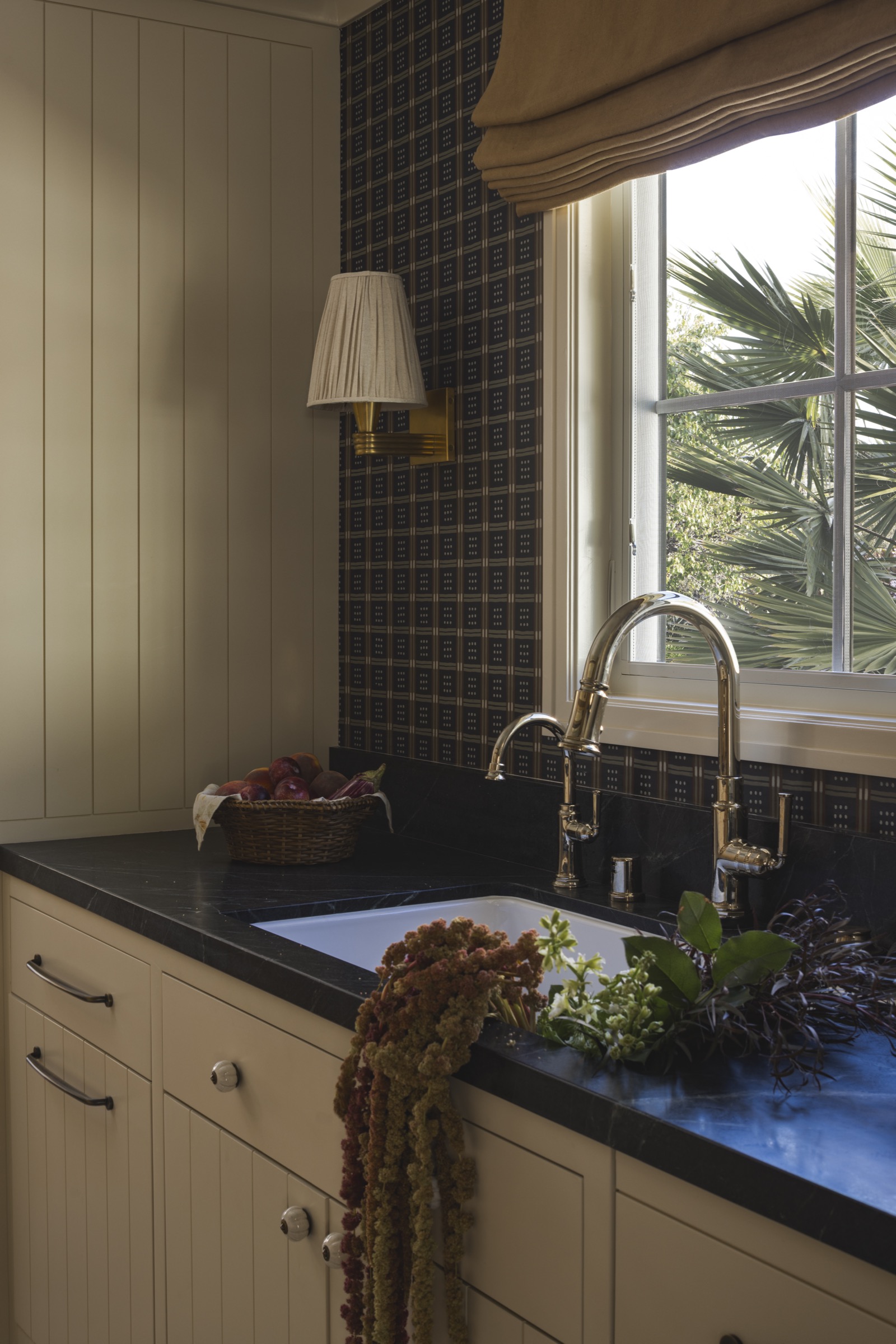Bright kitchen featuring a black countertop, white cabinetry, and a large window with a view of gree.