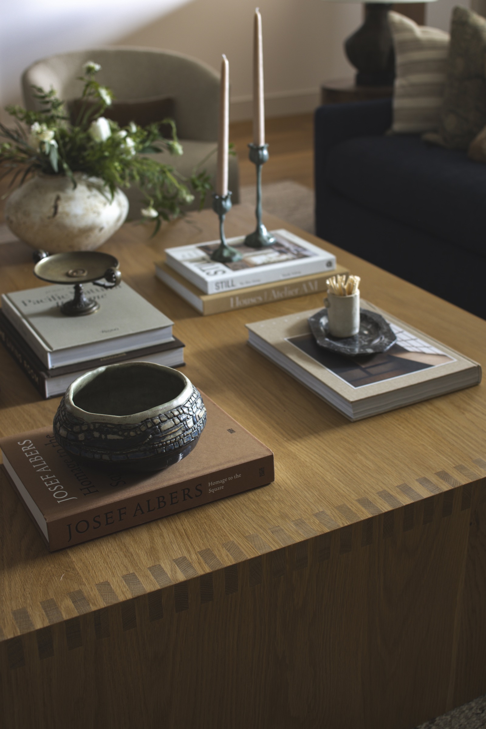 Elegant interior decor featuring stylish candles, books, and decorative bowls on a wooden table.